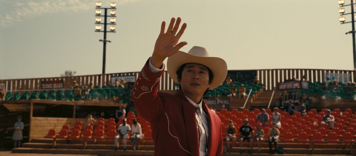 Steven Yeun, dressed for a cartoon rodeo, gestures towards the unknown in Jordan Peele's NOPE.