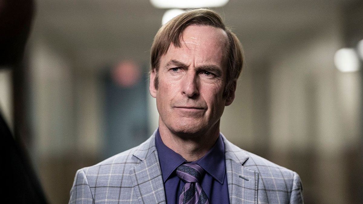 Bob Odenkirk wears a gray patterned suit jacket over a blue shirt and purple tie in a still from BETTER CALL SAUL.