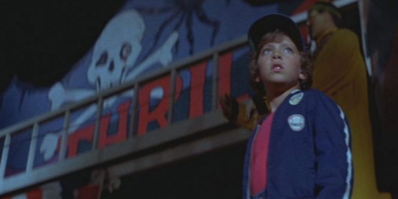 A young boy looks worried outside a creepy carnival funhouse, which to be honest is the appropriate reaction.